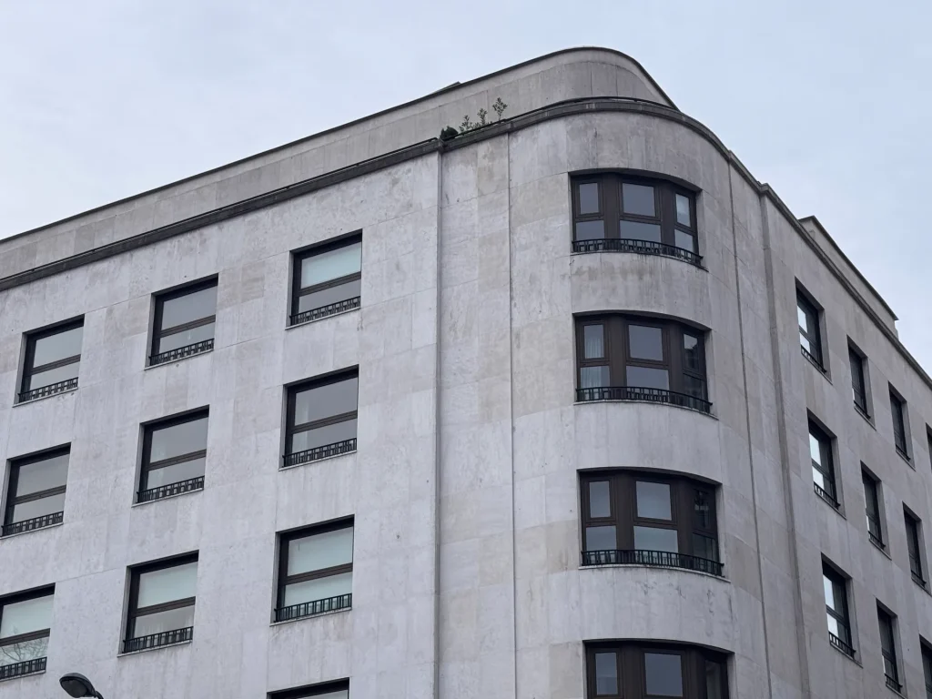 Esquina curva de un edificio de piedra clara con ventanas de madera oscura en Bilbao